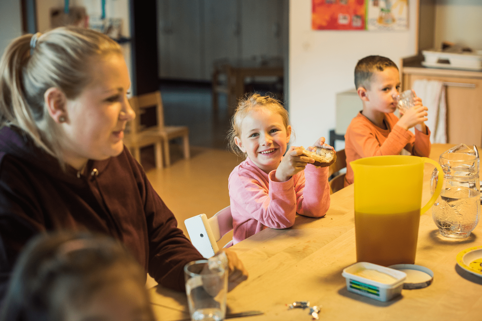Mädchen sitzt genüsslich am Tisch mit Zvieribrot in der Hand.