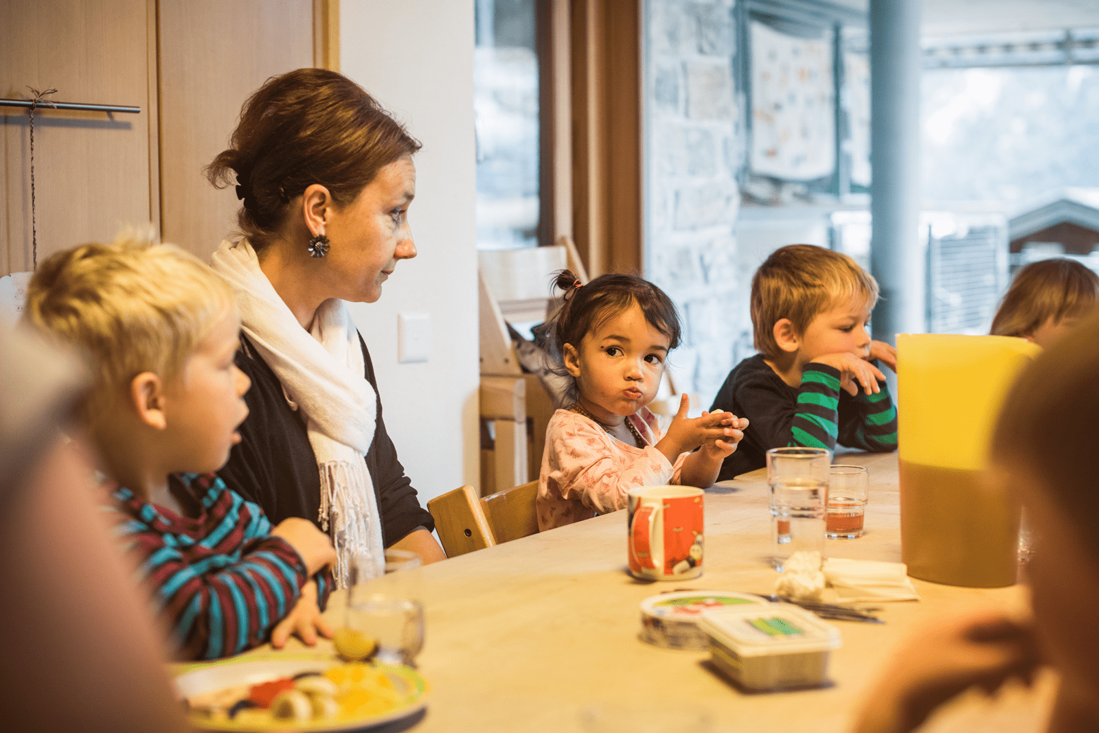 Kinder und Kita-Leiterin sitzen am Tisch und essen Znüni.